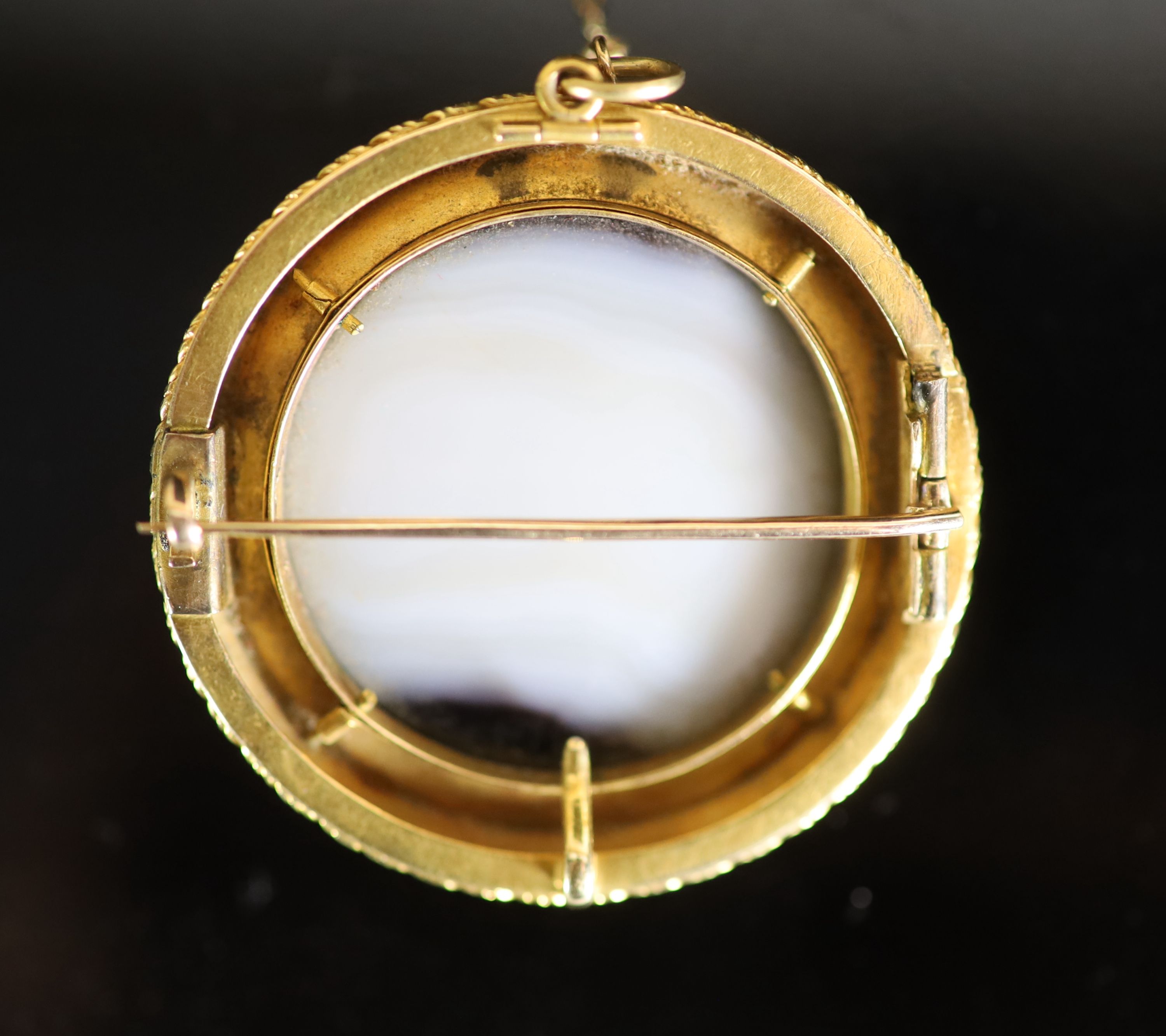 A Victorian gold and white enamel mounted agate cameo circular pendant brooch